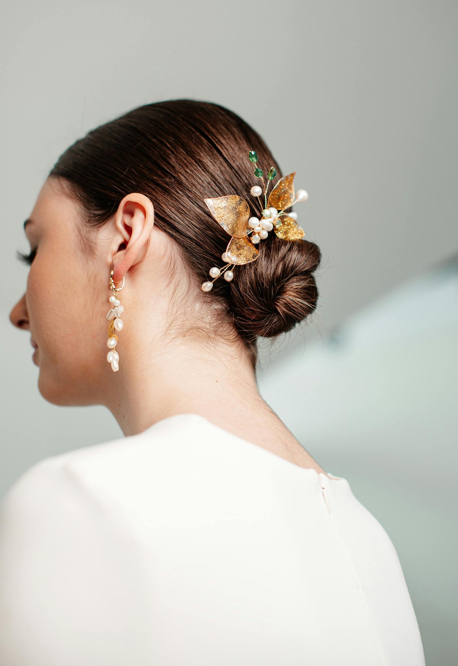 Close-up of a bridal hairstyle with delicate flower and pearl hair accessories.