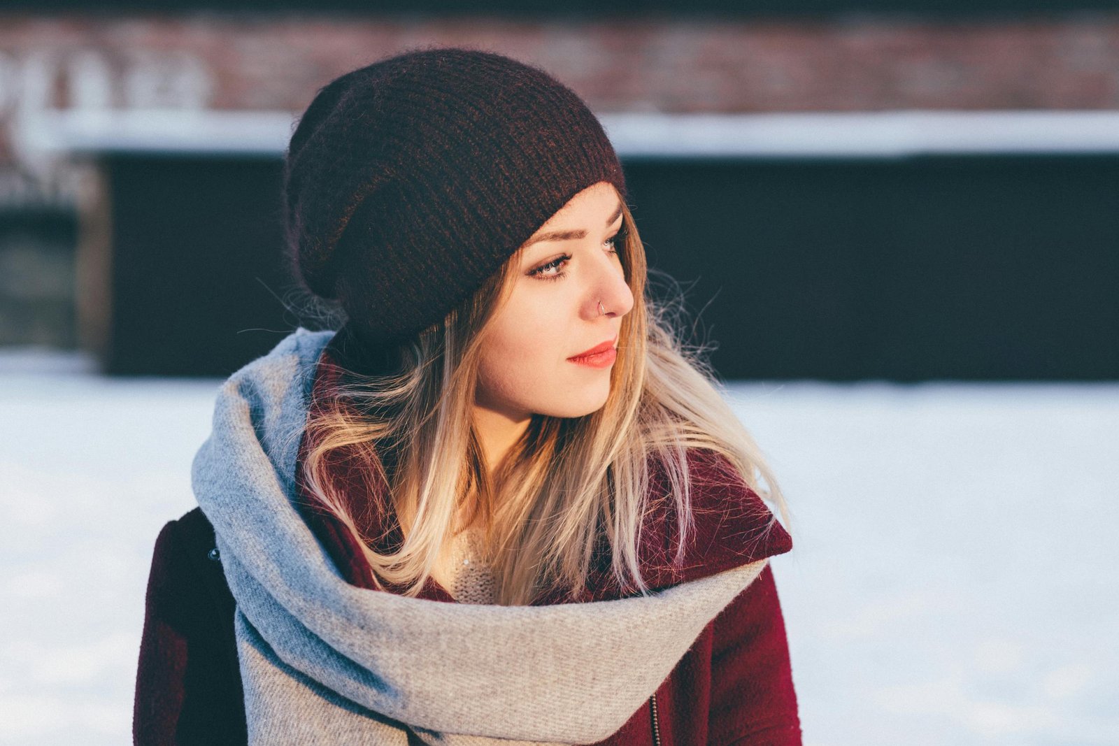 Fashionable woman in beanie and scarf outdoors during winter, showcasing a casual and cozy look.