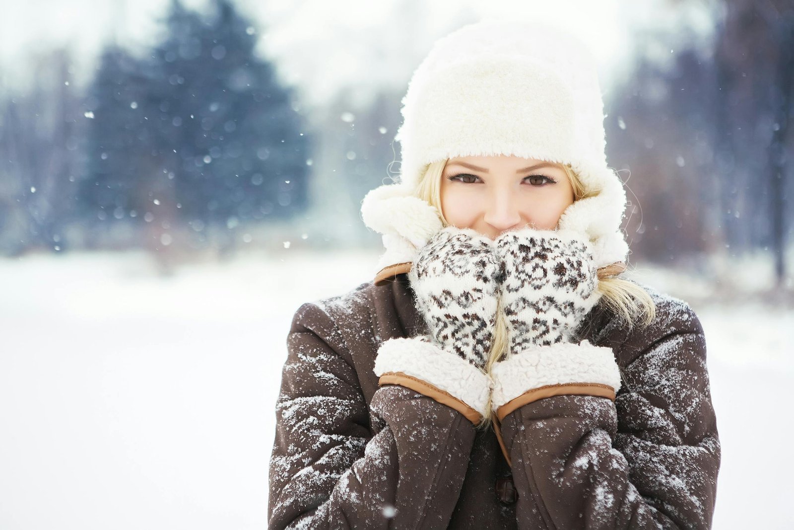 Portrait of a young woman enjoying a snowy winter day, bundled up in stylish clothes and smiling warmly.