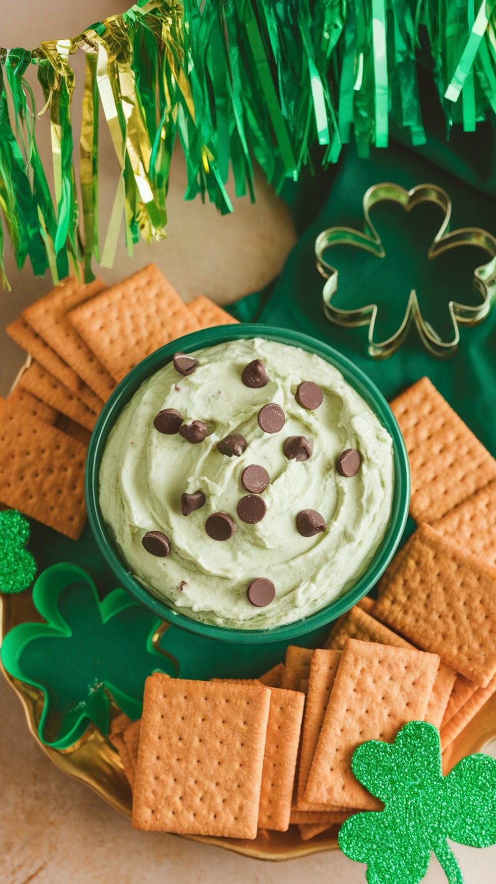 Mint chocolate chip dip in a green bowl surrounded by graham crackers and festive decorations.