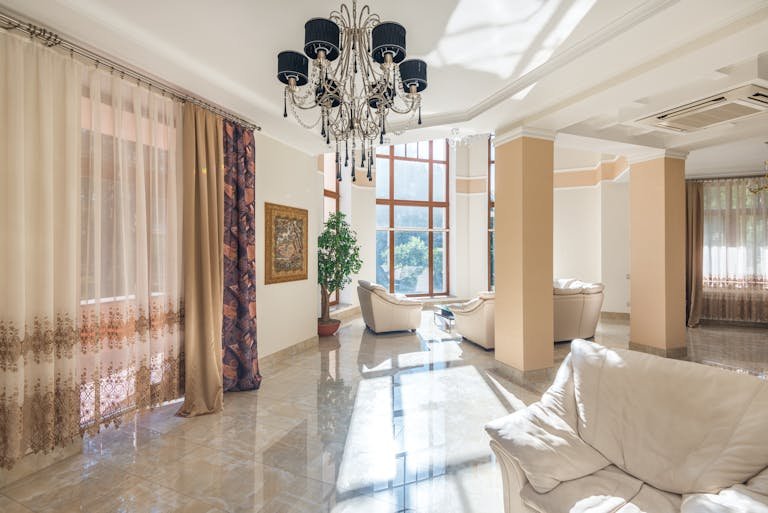 Spacious living room featuring elegant chandelier, large windows, and plush seating.